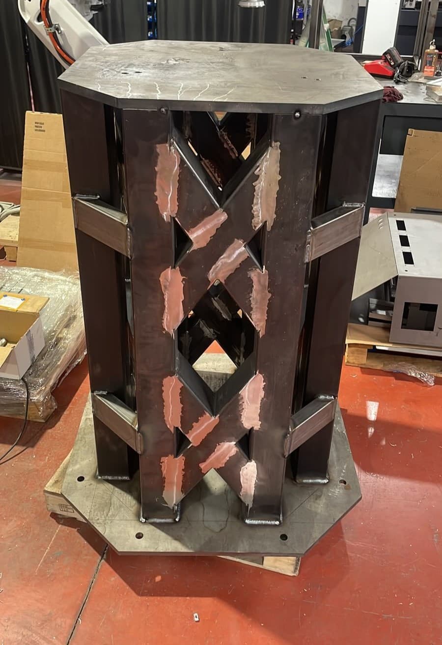 Peana de acero soldada con un robot industrial montado encima