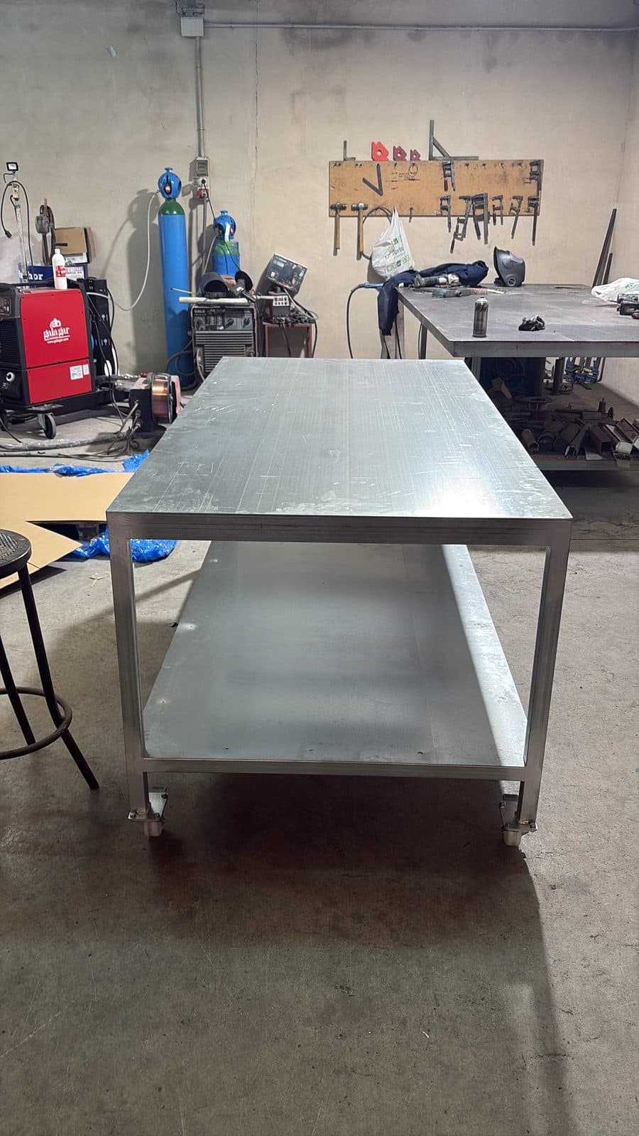 Mesa de trabajo de acero inoxidable con estante inferior en un taller