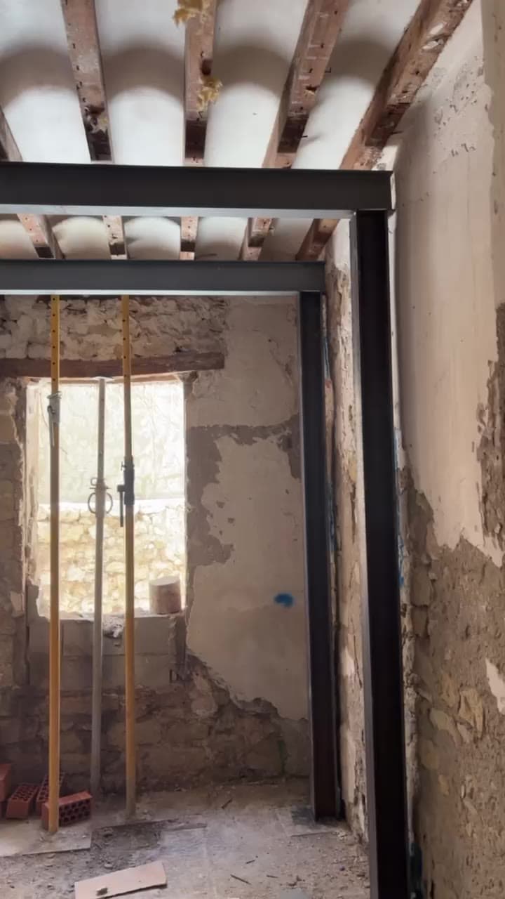 Vigas y pilares de acero instalados como refuerzo estructural bajo un forjado de madera, con puntales