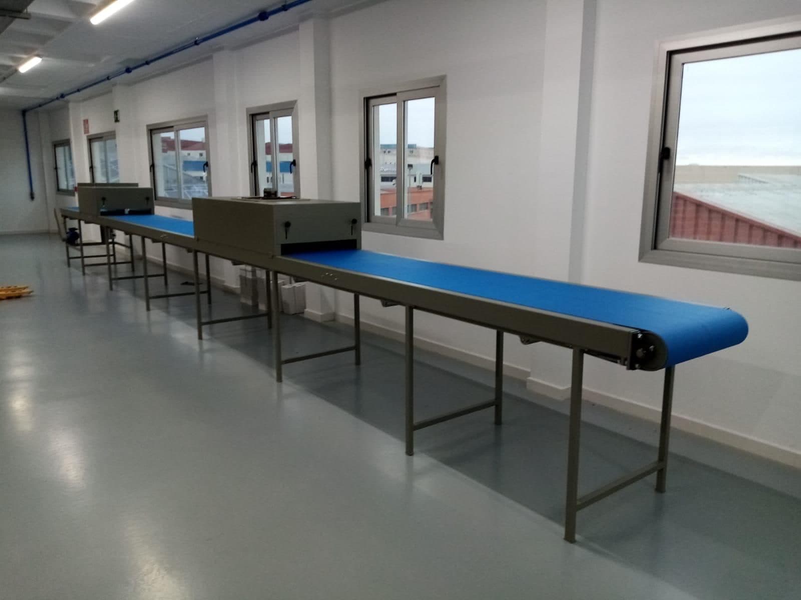 Línea de cintas transportadoras azules montada en una nave industrial