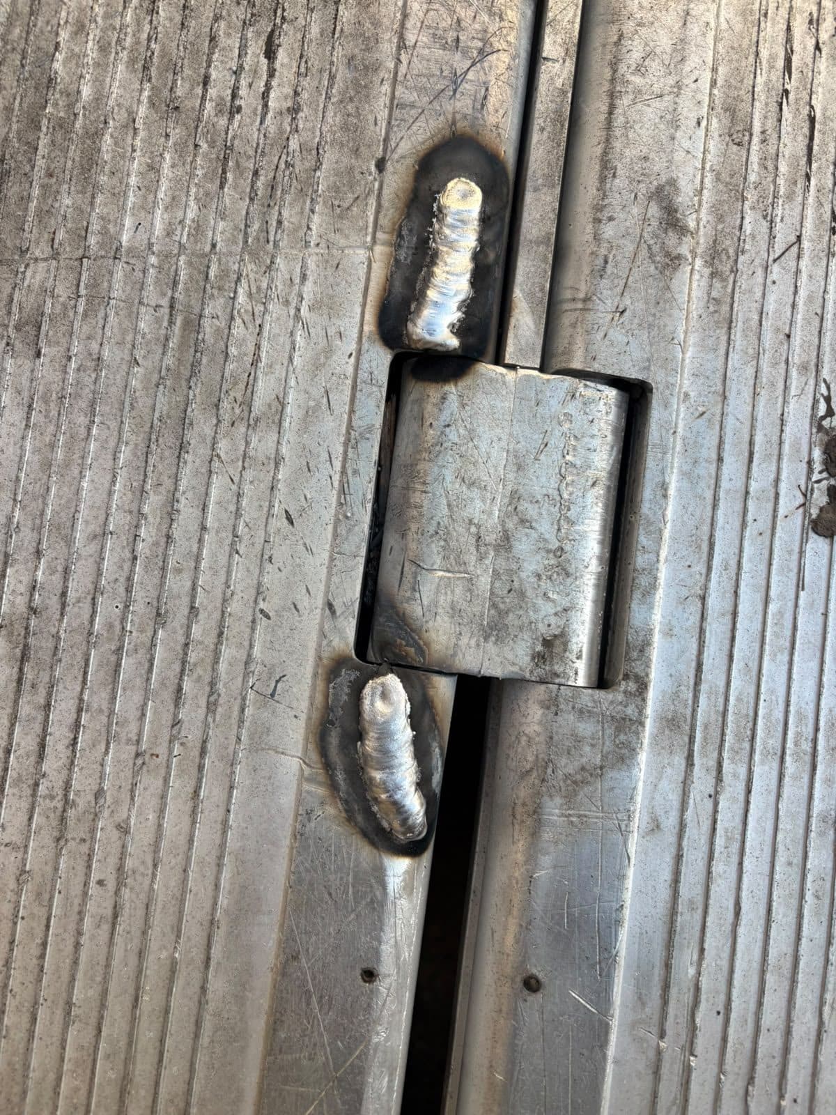 Bisagra de una puerta metálica reforzada con cordones de soldadura