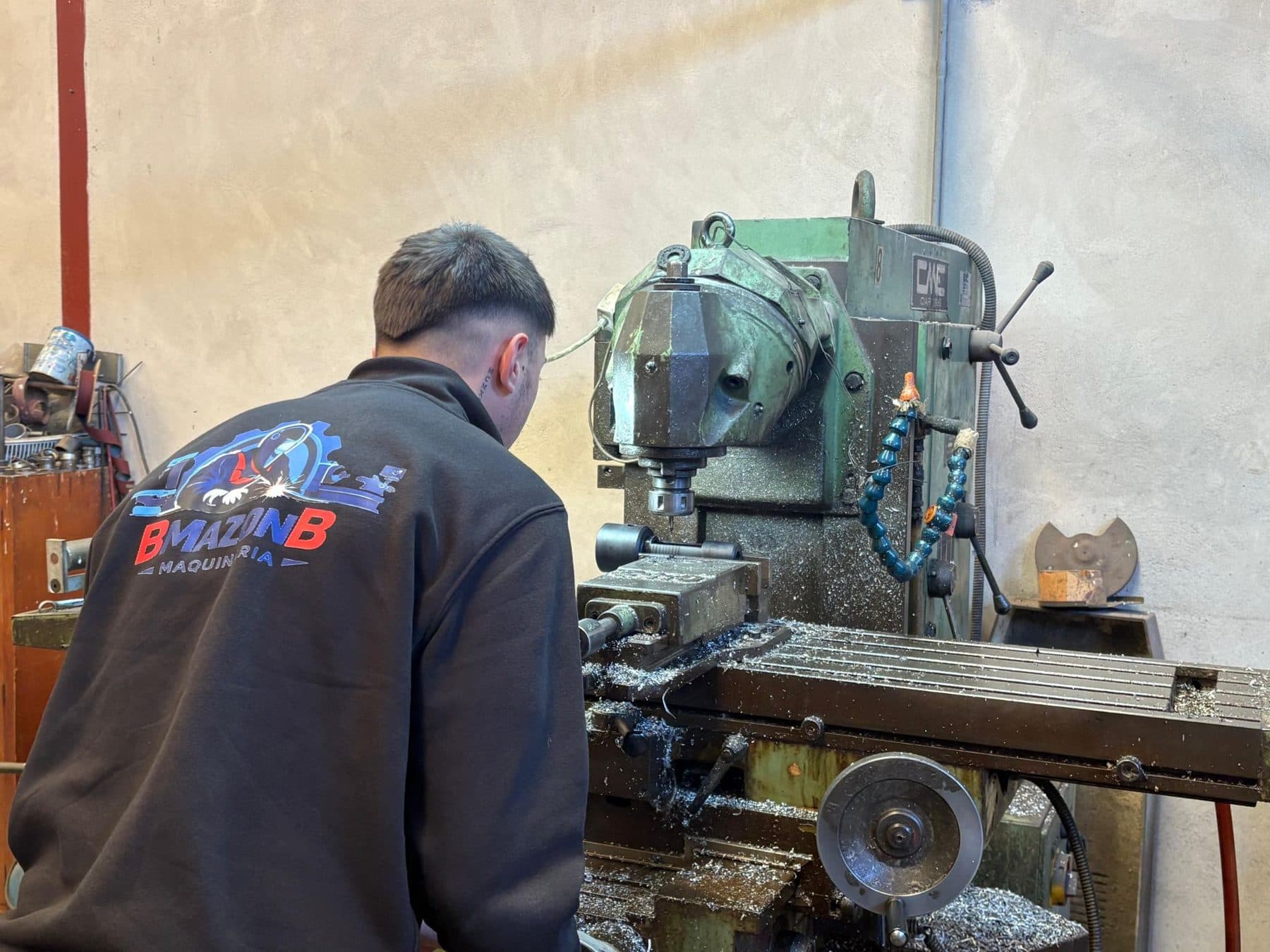 Borja trabajando en la fresadora con el logo de BMAZONB en la espalda